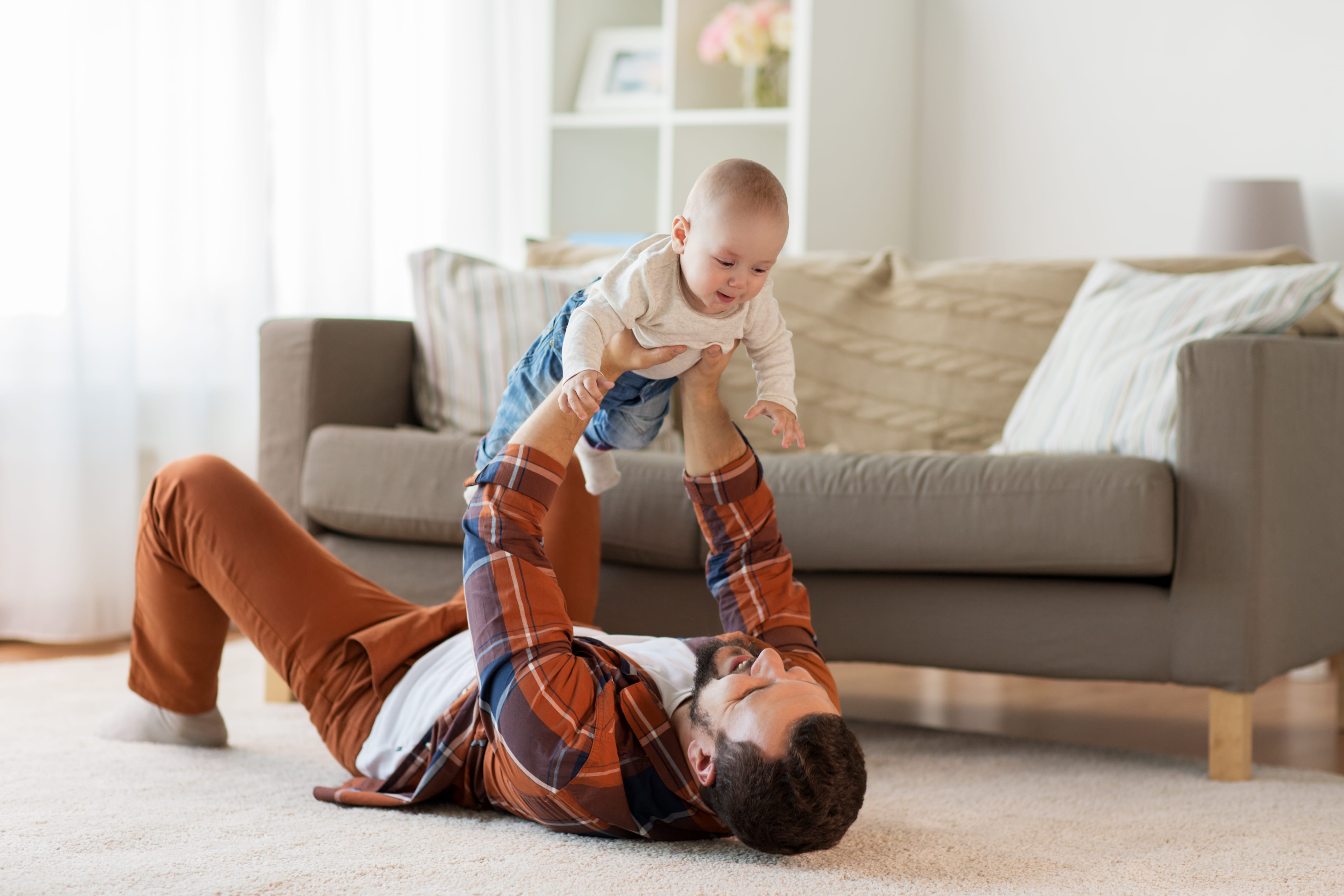 Happy Father with baby boy at home in living room by sofa