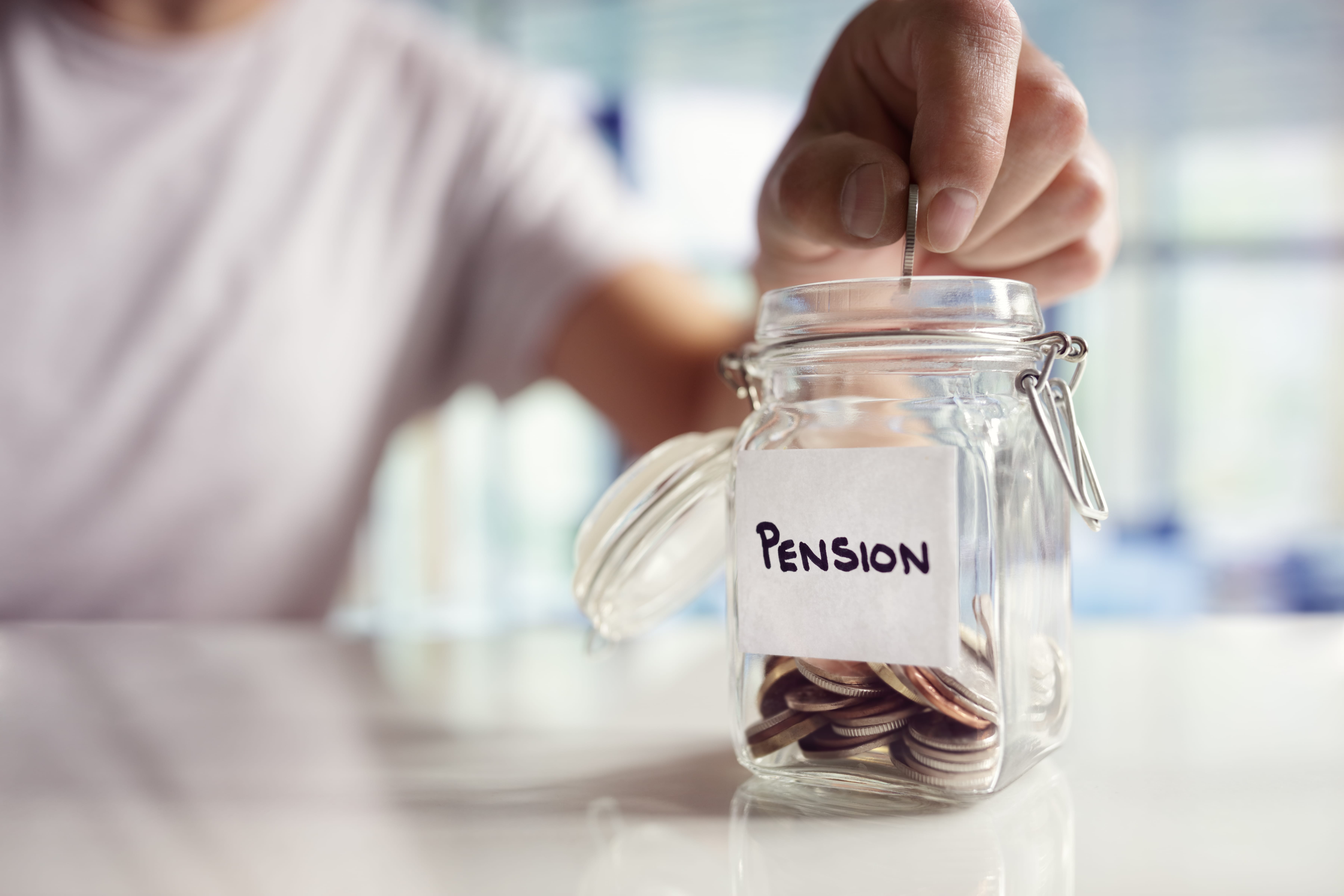 A man inserts a quarter into a mason jar labeled "Pension"